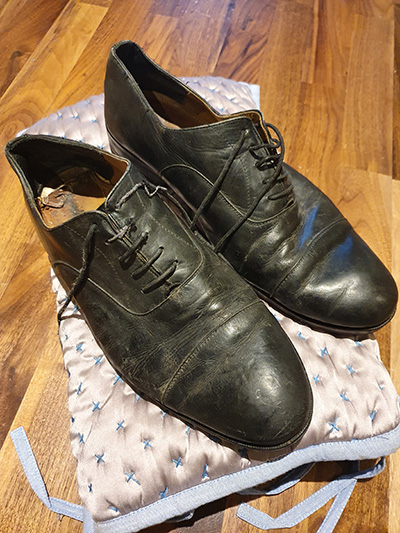 Pair of flattened, creased and heavily scuffed mens black derby shoes